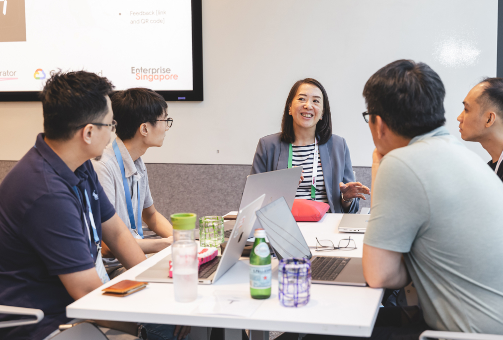 A group of people is listening carefully to a woman explaining something to them.