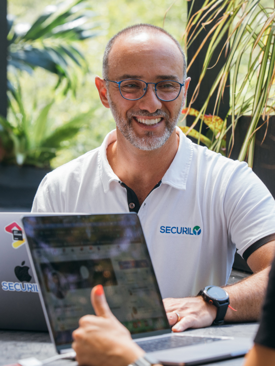 A bespectacled man with a smile on his face is talking with a woman.